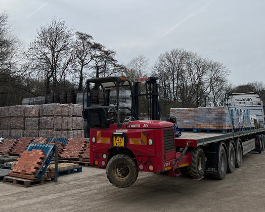 Red forklift with pallets on a dirt road