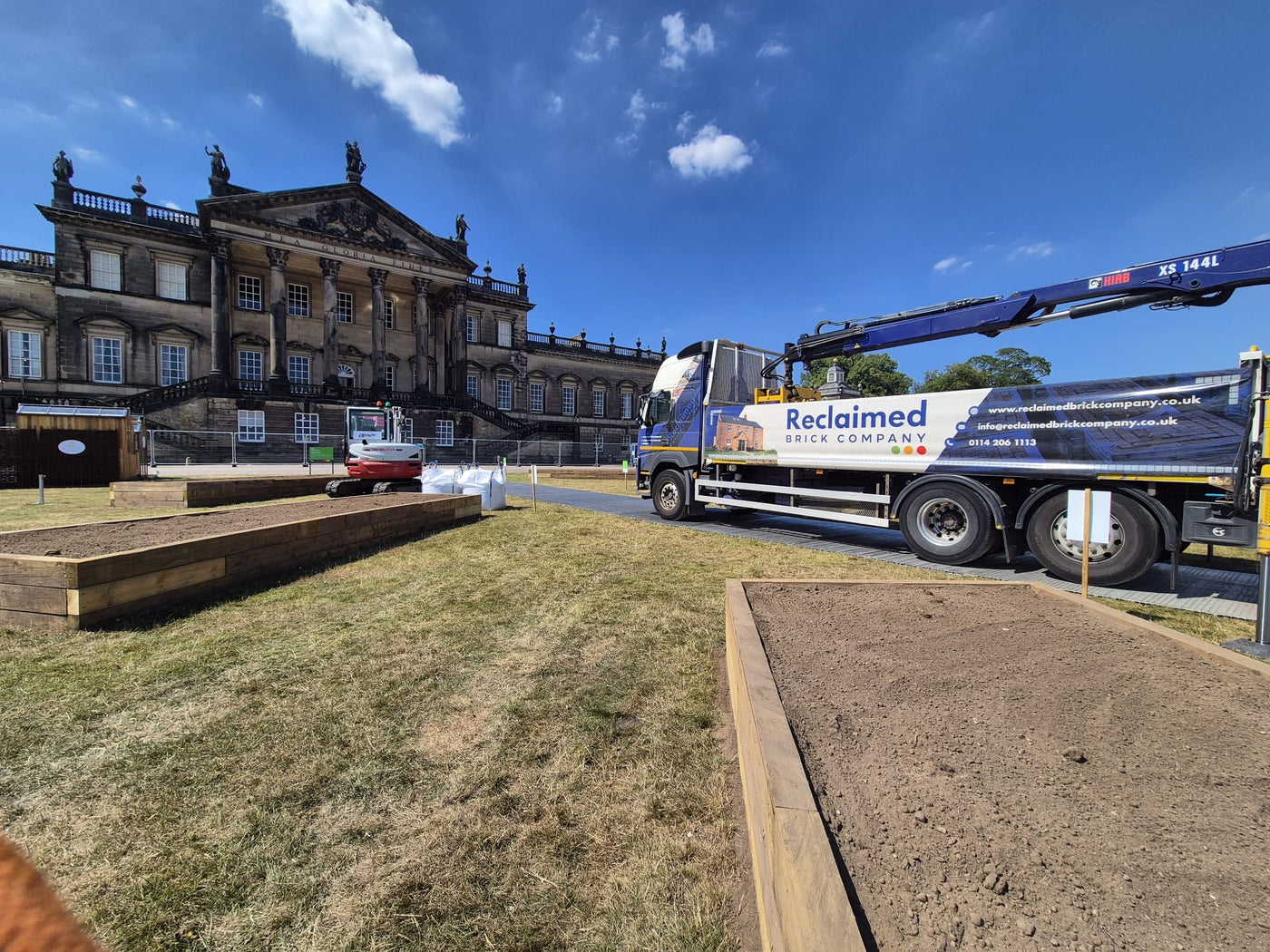 Truck with 'Reclaimed' branding in front of a large building under a blue sky.