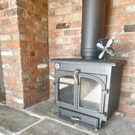 Black wood stove installed in a brick wall.