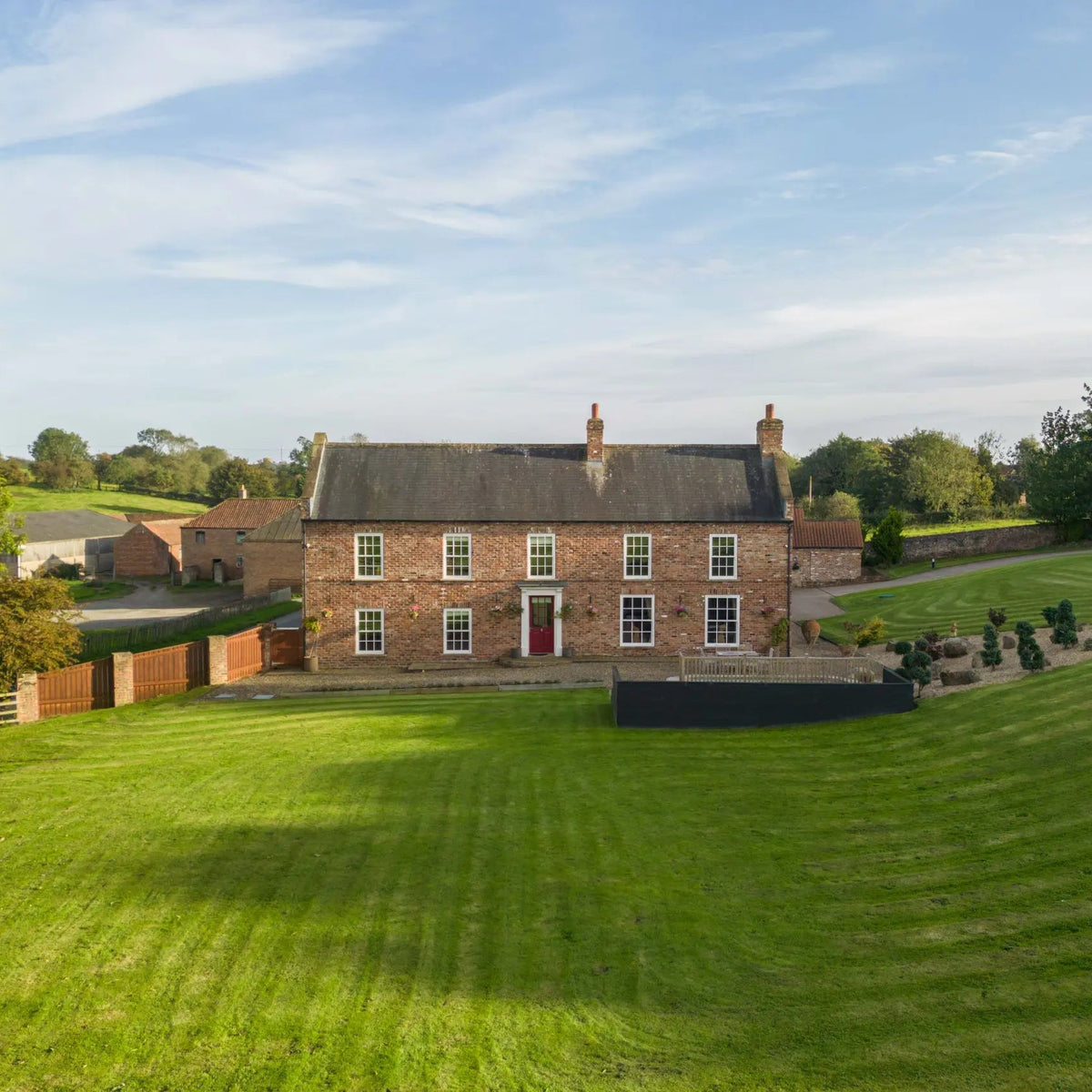 Large brick house with a well-maintained lawn and trees in the background