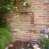 Fountain with flowers against a brick wall