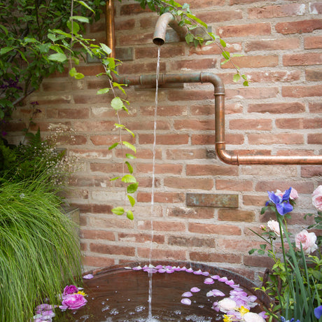 Fountain with flowers against a brick wall