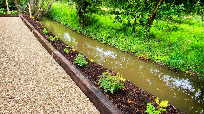 Reclaimed hardwood railway sleepers installed as garden border edging.