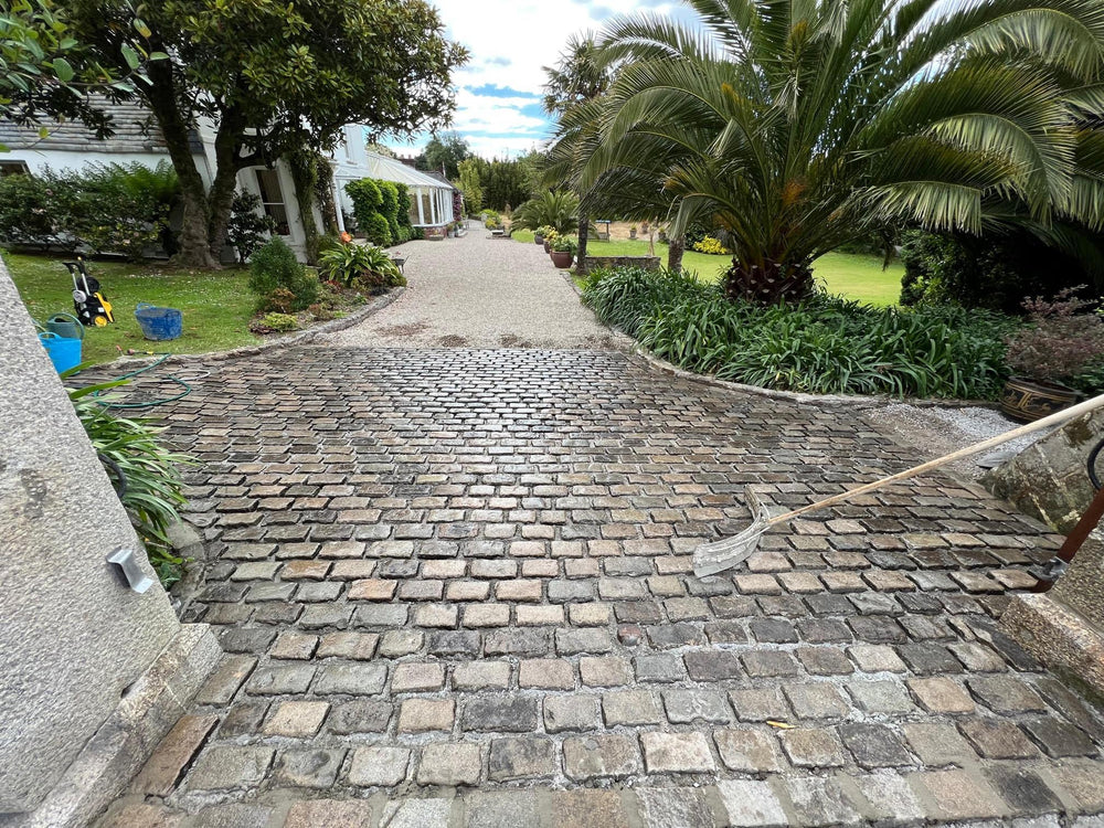 Reclaimed granite setts being cleaned and finished at a driveway entrance in Cornwall